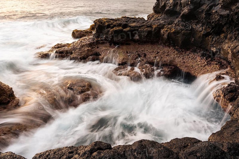 Seawater flows over lava rocks into a small pool. long exposure. Coast near Puerto de Talavera, La Palma, Canary Islands, Spain