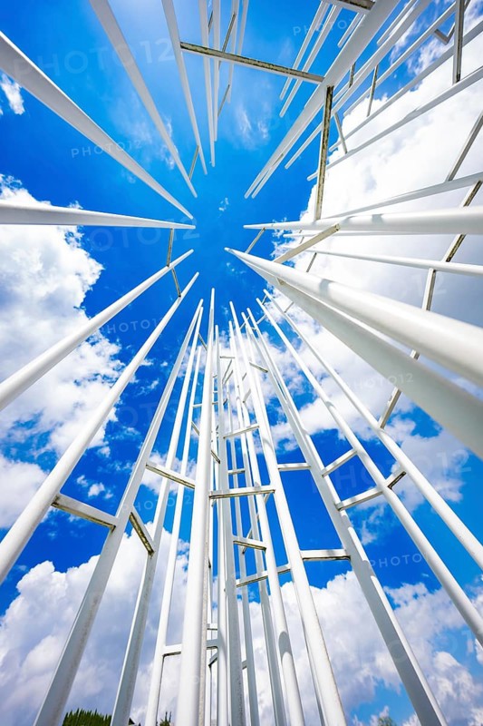 White poles rise up in an ornate pattern against a clear blue sky with clouds, Krumbach, Vorarlberg, Austria