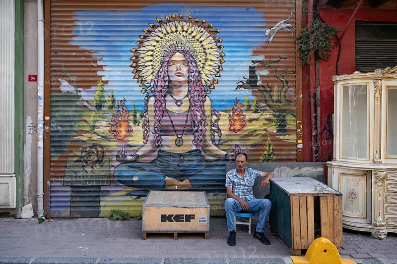 Istanbul, Turkey. August 8th 2026. A local man sits beside typical Bohemian style street art in the Balat neighbourhood of Istanbul, a diverse and trendy district of colourful houses, cafes and antique shops. Turkey