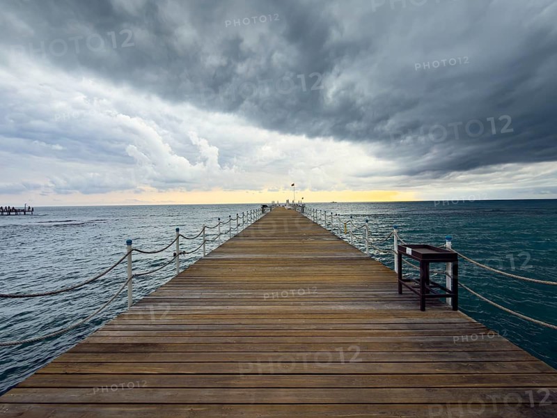 A wooden walkway leads into a stormy sea under a dramatic sky, Side, Manavgat, Antalya Province, Turkey