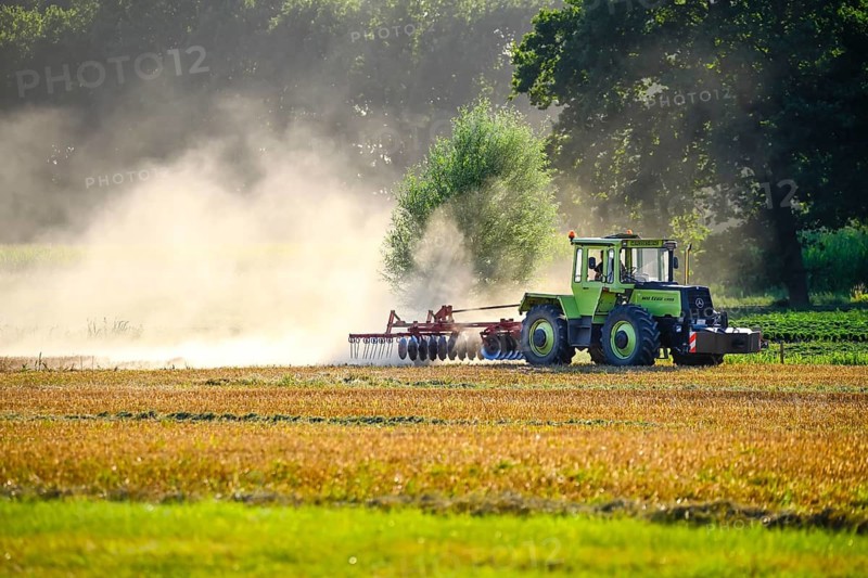 Tractor ploughs a harvested field in a cloud of dust in Kirchwerder, Hamburg, Germany +++ editorial use only