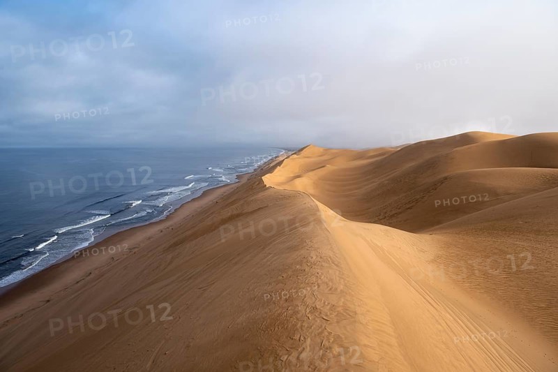 Sand dunes and sea in the morning, Atlantic coast and sandy desert with sea of dunes, Sandwich Harbour, Namib Naukluft Park, Namib Desert, Namibia