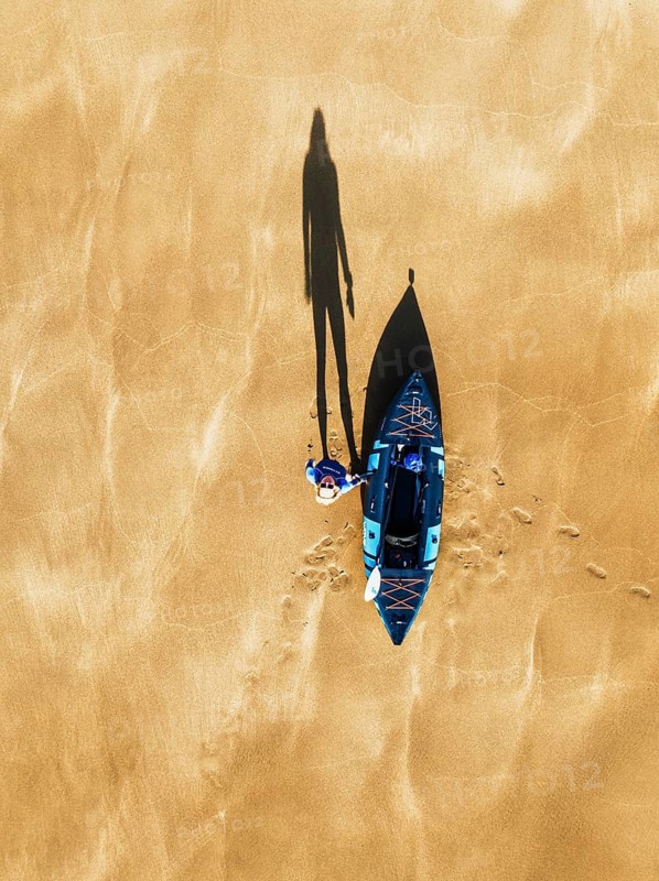 Top Down view fo woman with kayak over Beach from a drone, North Devon and Cornwall Coastpath Border from a drone, Welcombe Mouth Beach, Devon, Cornwall, England, United Kingdom