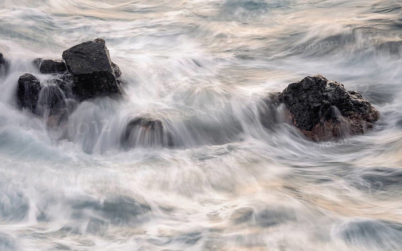 Rocks in the ocean, washed by waves. Long exposure, evening. Playa de Nogales, La Palma, Canary Islands, Spain
