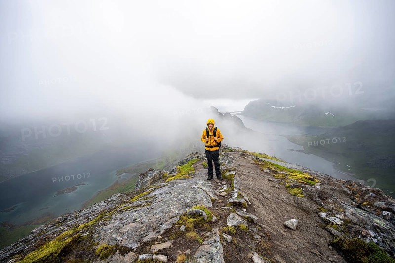 Hikers on Helvetestinden summit, covered in clouds, Lofoten, Norway