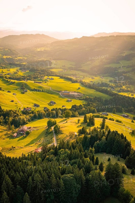 Wide hills and forest landscape viewed from the air under low sun, Oberstaufen region, Allgäu, Bavaria, Germany