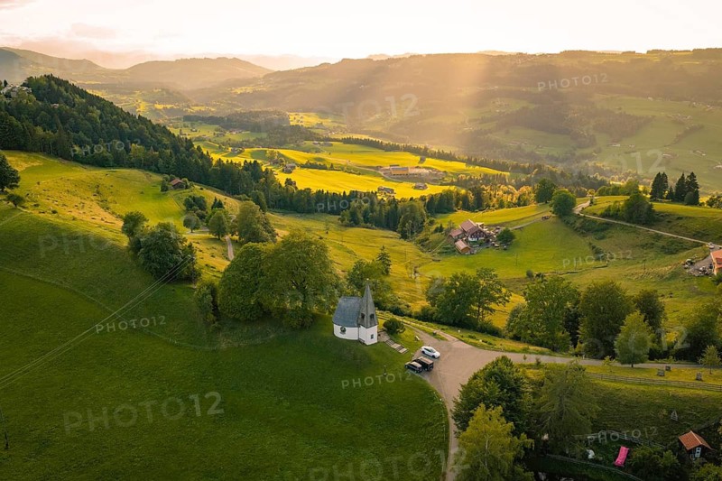 Wide landscape with chapel surrounded by forests and fields in the evening light, Bruder Klaus Kapelle, Allgäu, Bavaria, Germany