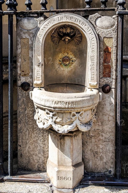 A marble drinking fountain of Welsh and Italian marble stands in the churchyard railings of St Dunstan-in-the-West on Fleet Street, unveiled in 1860 and inscribed as the gift of Sir James Duke, Baronet, Member of Parliament and Alderman of the ward of Farringdon. London, England, United Kingdom