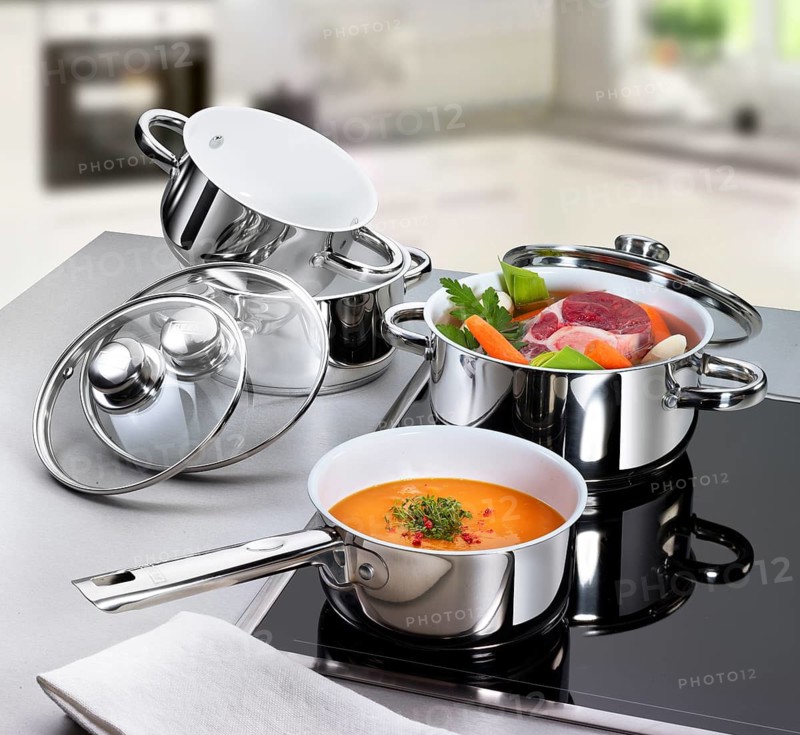 Hob with various pots, including soup meat with vegetables, prepared soup in front of it, studio shot