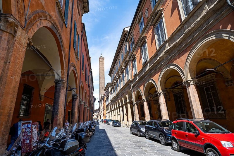 Portici arcades and historic buildings in Strada Maggiore, behind Asinelli Tower of Due Torri, old town, Bologna, Emilia Romagna, Italy