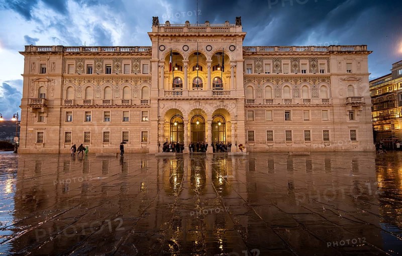 Illuminated square Piazza Unità d'Italia, Palazzo della Luogotenenza Austriaca or Palazzo Governo, with reflection, dramatic clouds, blue hour, old town, Trieste, Friuli-Venezia Giulia region, Italy