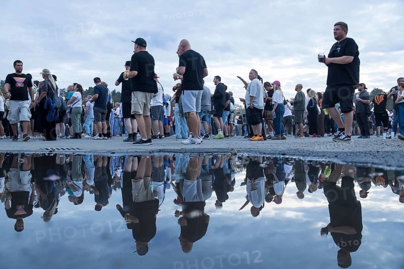 Festival visitors are reflected in a puddle at the Klassentreffen festival on the Central Fairground in Berlin on 29.08.2026