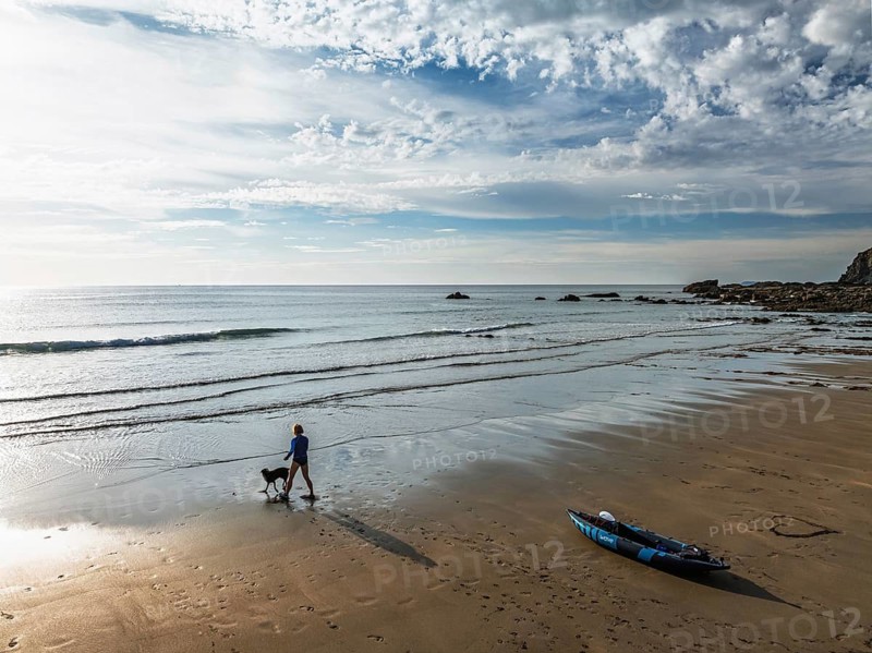 Woman and dog with kayak on Beach from a drone, North Devon and Cornwall Coastpath Border from a drone, Welcombe Mouth Beach, Devon, Cornwall, England, United Kingdom