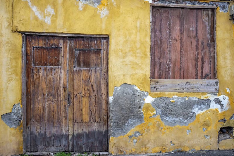 Weathered façade of an empty house in Garachico, characterized by crumbling plaster and old wooden doors, a silent testimony of past times, Garachico, Tenerife, Canary Islands, Spain