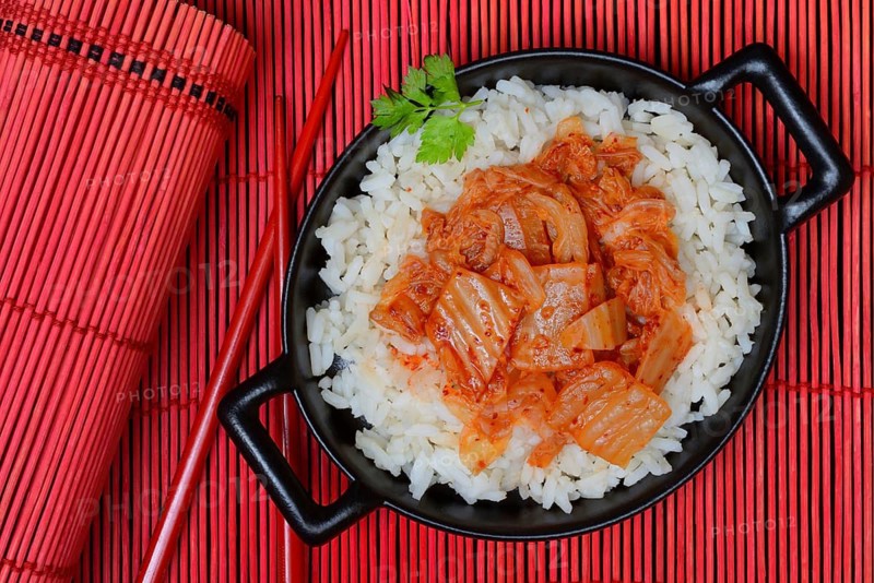 Kimchi, fermented vegetables on rice in bowl with chopsticks