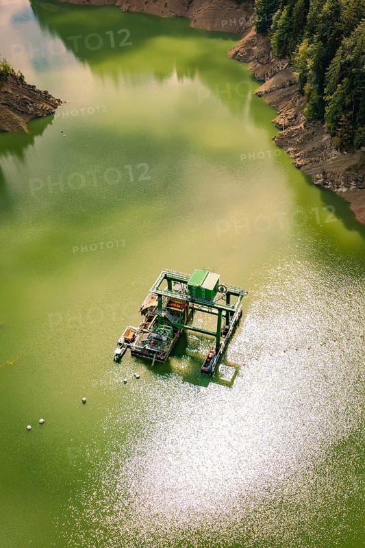 A technical platform floats on a greenish body of water, sparkling in sunlight, Krumbach, Vorarlberg, Austria