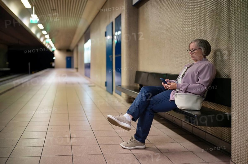 Elderly woman sitting on bench, lonely, alone, waiting in Maybachstraße subway station for light rail, empty, stop, subway, light rail, platform, train station, public transport, Stuttgart, Baden-Württemberg, Germany