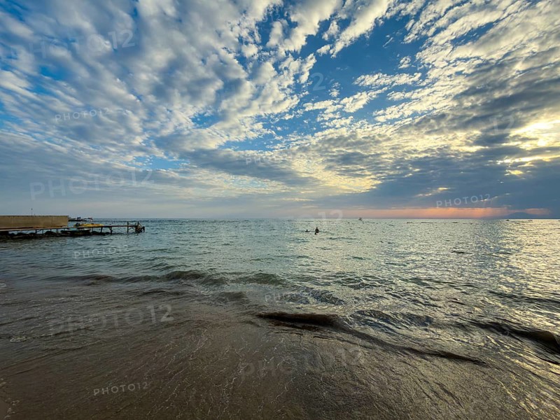 Cloudburst at sunset over calm sea with gentle waves on beach, Side, Manavgat, Antalya Province, Turkey