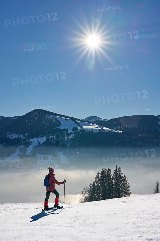 Sportive senior woman hiking with snow shoes in the snowy Allgaeu Alps above Lake Alosee, Immenstadt, Bavria, Germany