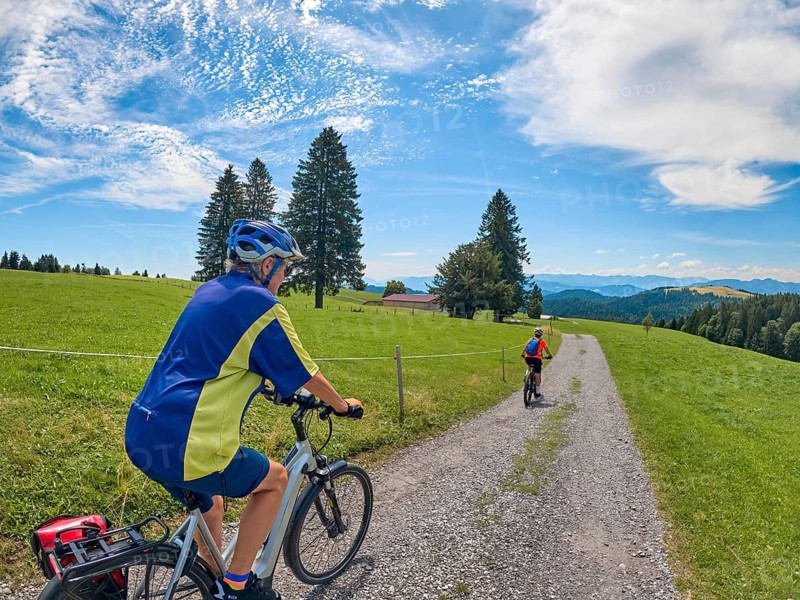 Two senior girlfriends have fun during a e-bike cycling tour in the Allgau Alps near Oberstaufen, Bavaria, Germany