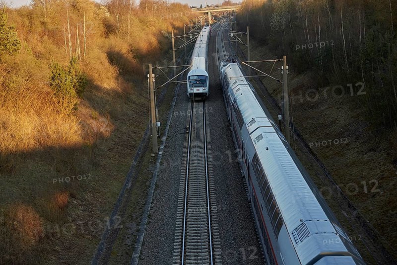 Train traveling through a scenic railway corridor at sunset, surrounded by trees and overhead power lines. Stuttgart to Mannheim, Baden-Württemberg, Germany