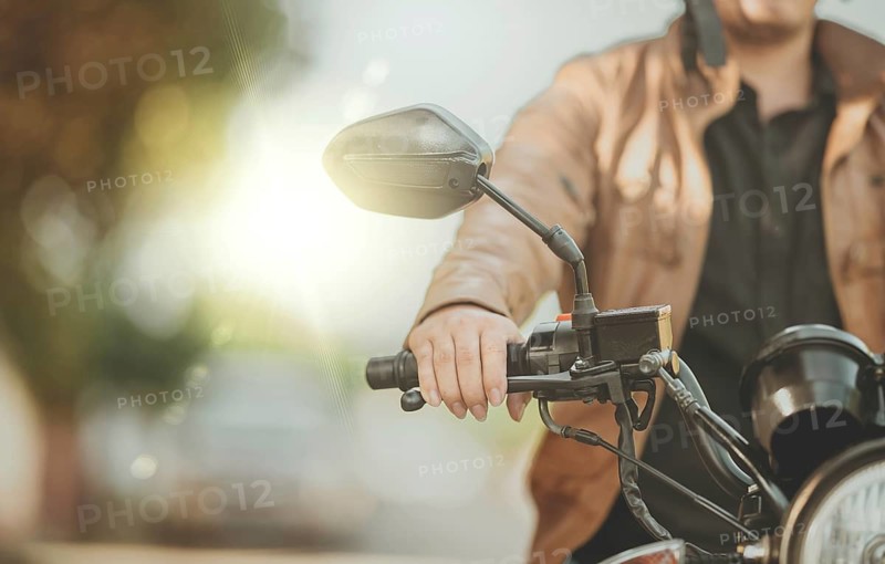 Close up of hands of biker on the handlebars of a motorcycle outdoors. Hands of motorcyclist on the handlebars on the road