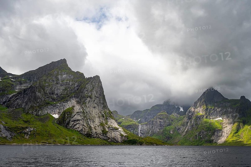 Waterfall and fjord landscape with mountains, Reinefjord, Lofoten, Norway