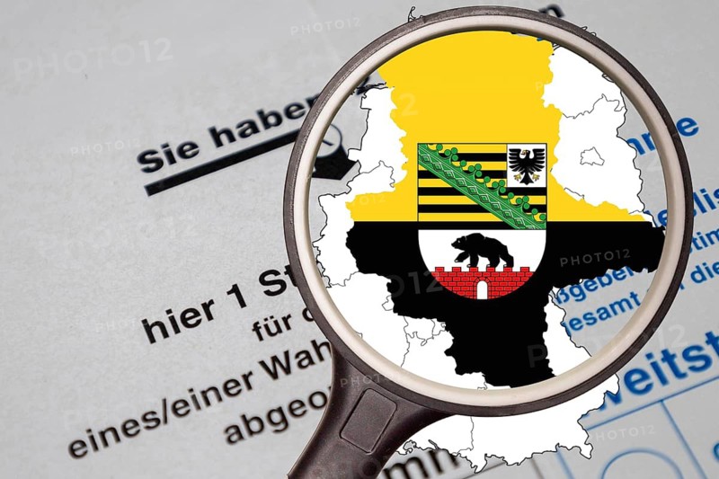 (Photomontage) Map of Saxony-Anhalt with the State Coat of Arms under a Magnifying Glass