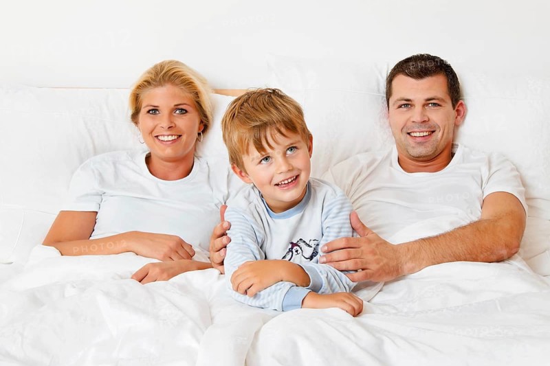 A family is lying in bed in the morning and having fun, Austria