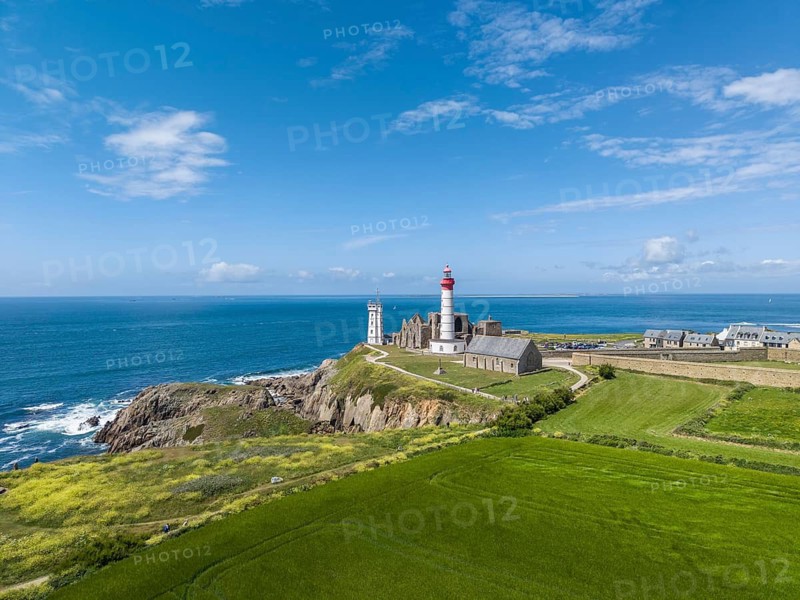 Aerial view of the distinctive red and white lighthouse Phare de Saint-Mathieu on the Breton coast next to the historic church ruins of the former Benedictine Abbey of Saint-Mathieu de Fine-Terre, next to it a white marine signal tower also called Sémaphor, Pointe Saint-Mathieu, Plougonvelin, Finistère department, Brittany region, France