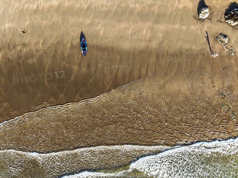 Top Down view fo woman with kayak over Beach from a drone, North Devon and Cornwall Coastpath Border from a drone, Welcombe Mouth Beach, Devon, Cornwall, England, United Kingdom