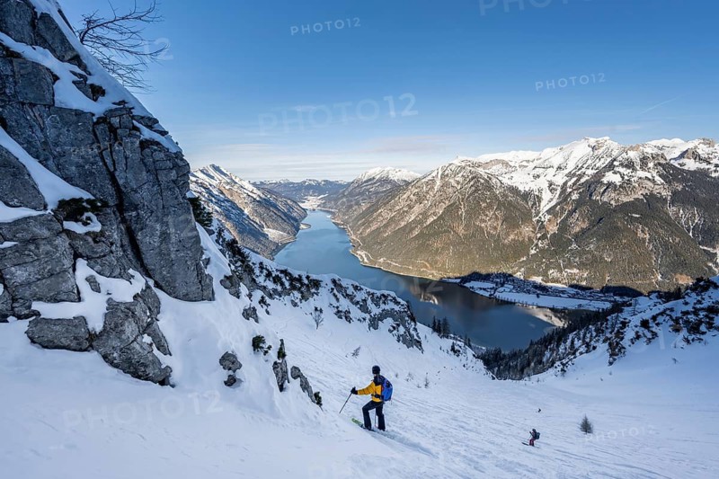 Picturesque view of Achensee and wintry mountain scenery, ski tourers descending from the summit of Bärenkopf, Achensee, Tyrol, Austria