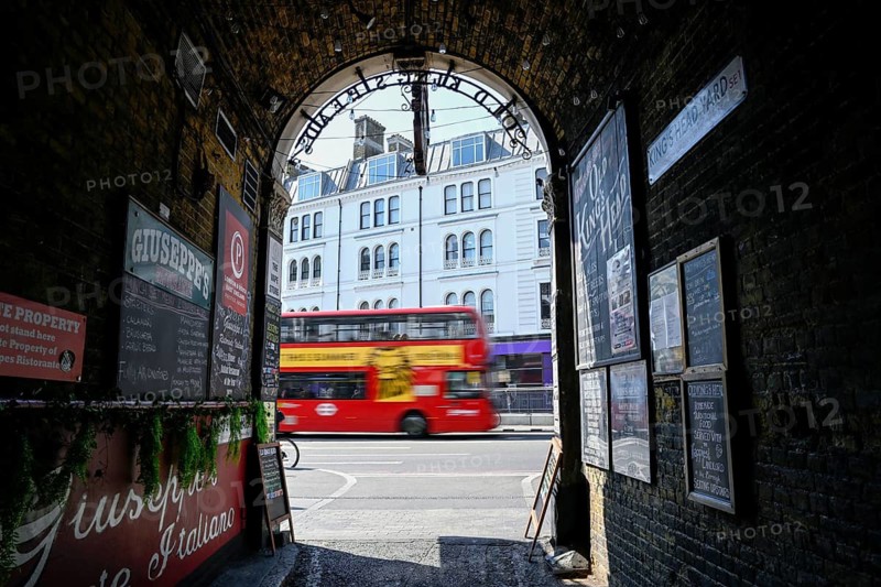 View through the archway of a historic pub onto a passing red double-decker bus, near London Bridge Station, Southwark, London, England, Great Britain, Great Britain