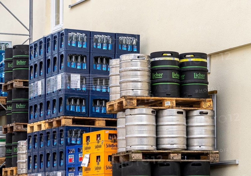 Beverage crates piled on pallets and beer kegs outside a beverage warehouse, Berlin, Germany
