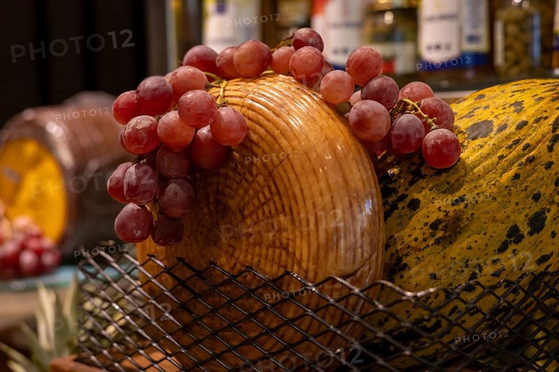 A basket filled with fresh red grapes sits atop a wooden cheese board. The cozy atmosphere enhances the appealing presentation of local delicacies. Snacks for wine