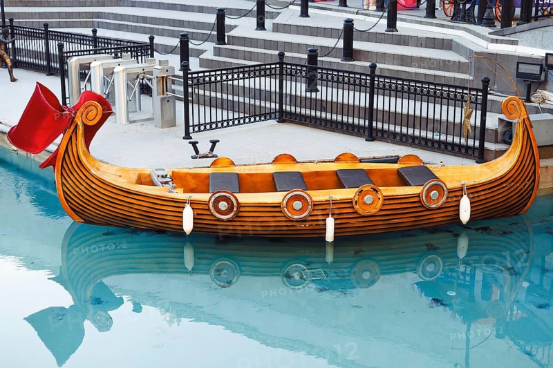 An empty fairy-tail boat gondola waits for tourists on a narrow canal. Summer suny day and transparent blue water