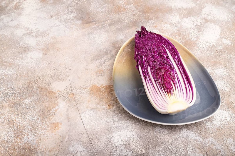Purple Chinese cabbage on blue plate on brown concrete background, side view, copy space, minimalism