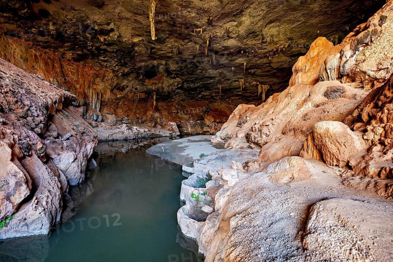 Cave with calm water surrounded by natural, earthy rock formations, The Gruta do Sumidouro in Campo Formoso in the state of Bahia Brazil