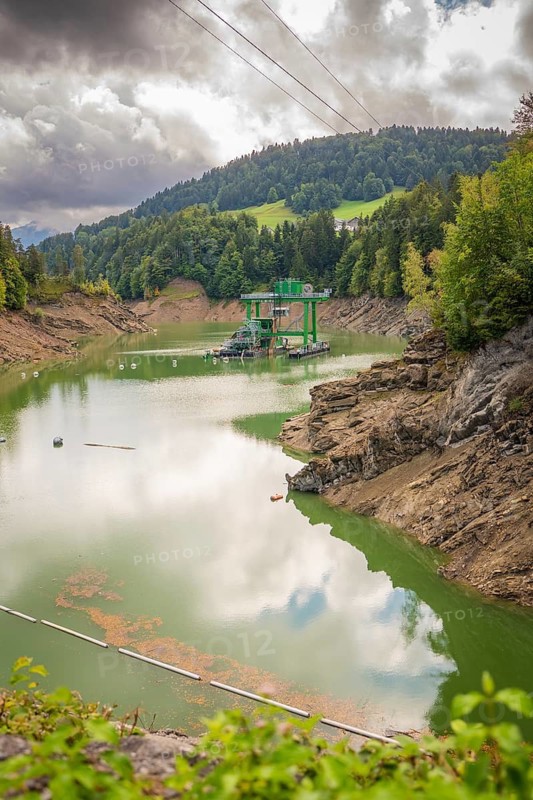 Mirror-smooth lake in forest environment with buoys, dramatically cloudy sky, Krumbach, Vorarlberg, Austria