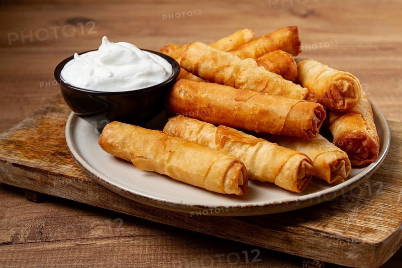 Fried spring rolls with cheese, on a wooden background, with cream sauce, no people