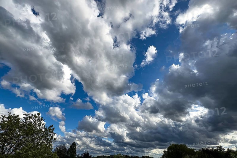 Large cloud field of dark cumulus cluster clouds at the bottom announce rain clouds rain front on the right, international
