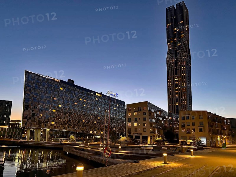 Modern buildings at dusk with reflecting facades and calm water surface in the foreground, Karlatornet, tallest building in Scandinavia, Eriksberg, Gothenburg, Sweden