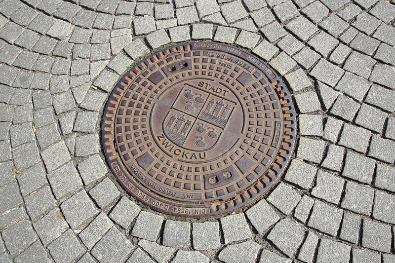 Round manhole cover with city coat of arms and inscription, paving stones, Zentrum station, Zwickau, Saxony, Germany