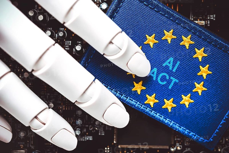 Robot hand on computer board and EU flag with AI Act lettering, photo montage +++ editorial use only