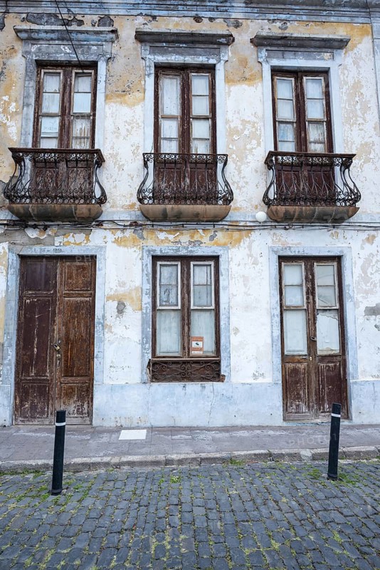 Weathered façade of an empty house in Garachico, characterized by crumbling plaster, old wooden doors and wrought-iron balconies, a silent testimony of past times, Garachico, Tenerife, Canary Islands, Spain