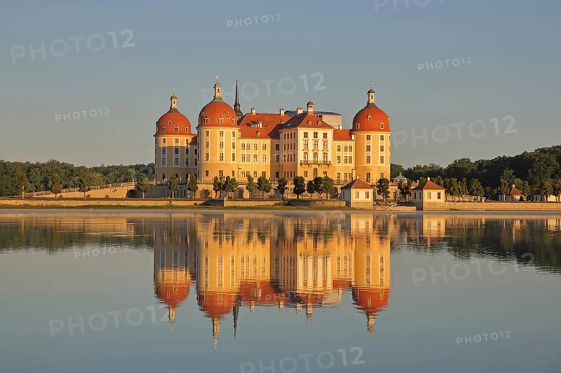 Baroque castle with reflection in the lake, yellow baroque castle with corner towers, lighting atmosphere, Moritzburg, Saxony, Germany