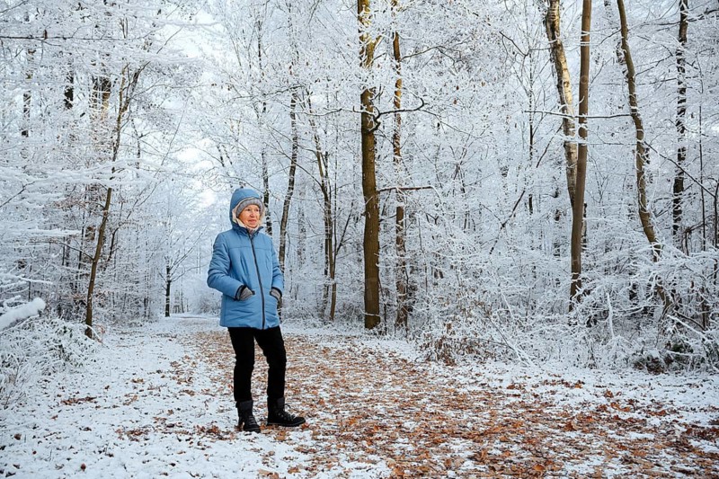 Woman standing on a forest path in winter, Beversee Nature Reserve, Bergkamen, North Rhine-Westphalia, Germany