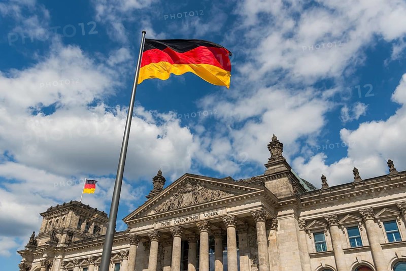 German flags are blowing in the wind in front of the German Reichstag in sunshine and blue sky, Berlin