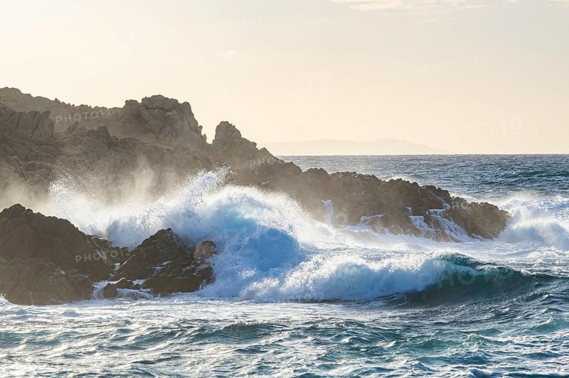 Braking waves at the coastline of Marinedda Coast at sunset, Sardinia, Italy