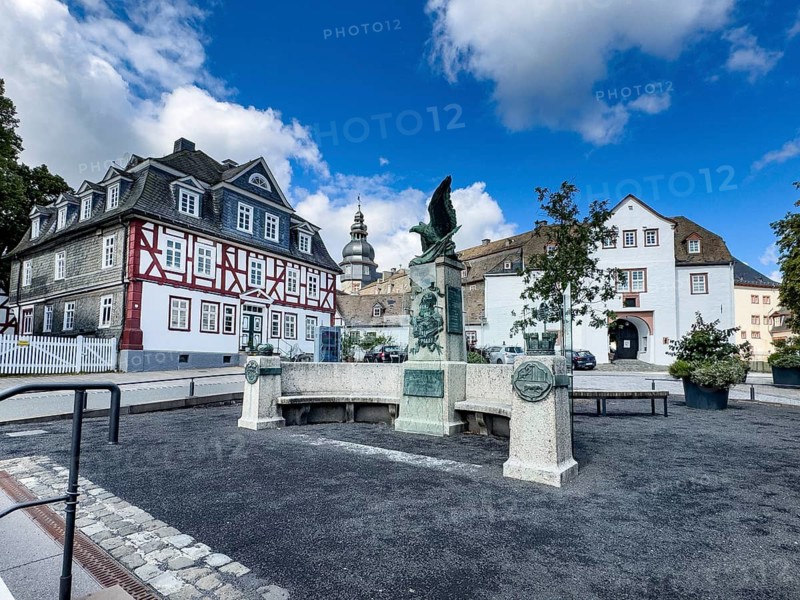 Original historic war memorial converted into a peace memorial in 2023 Memorial to Unification Wars with eagle and relief of Emperor Wilhelm I and memorial plaque with inscription To the unforgettable hero emperor Wilhelm I and the sons who fell for the fatherland the grateful county of Wittgenstein-Berleburg, Bad Berleburg, right in the background gatehouse of Berleburg Castle on the city side, left old half-timbered house, Bad Berleburg, North Rhine-Westphalia, Germany